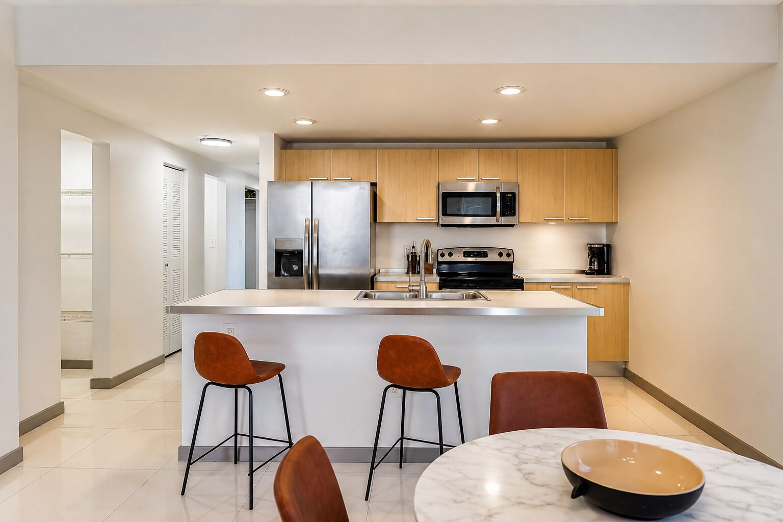 Une cuisine moderne dotée d’un îlot central, d’appareils électroménagers en acier inoxydable et d’armoires en bois.