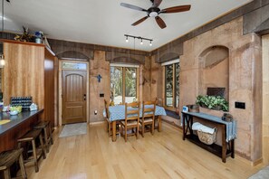 A dining area with a wooden table and chairs, a ceiling fan, and a view of the outdoors through large windows. - Casa AHORA - Unique 2 bdrm 2 bath full house in Prescott (Prescott)