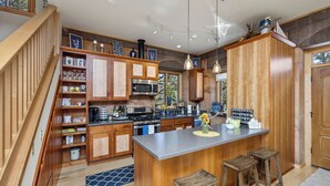 Una cocina con armarios de madera, una isla central con taburetes, un microondas y una estufa.