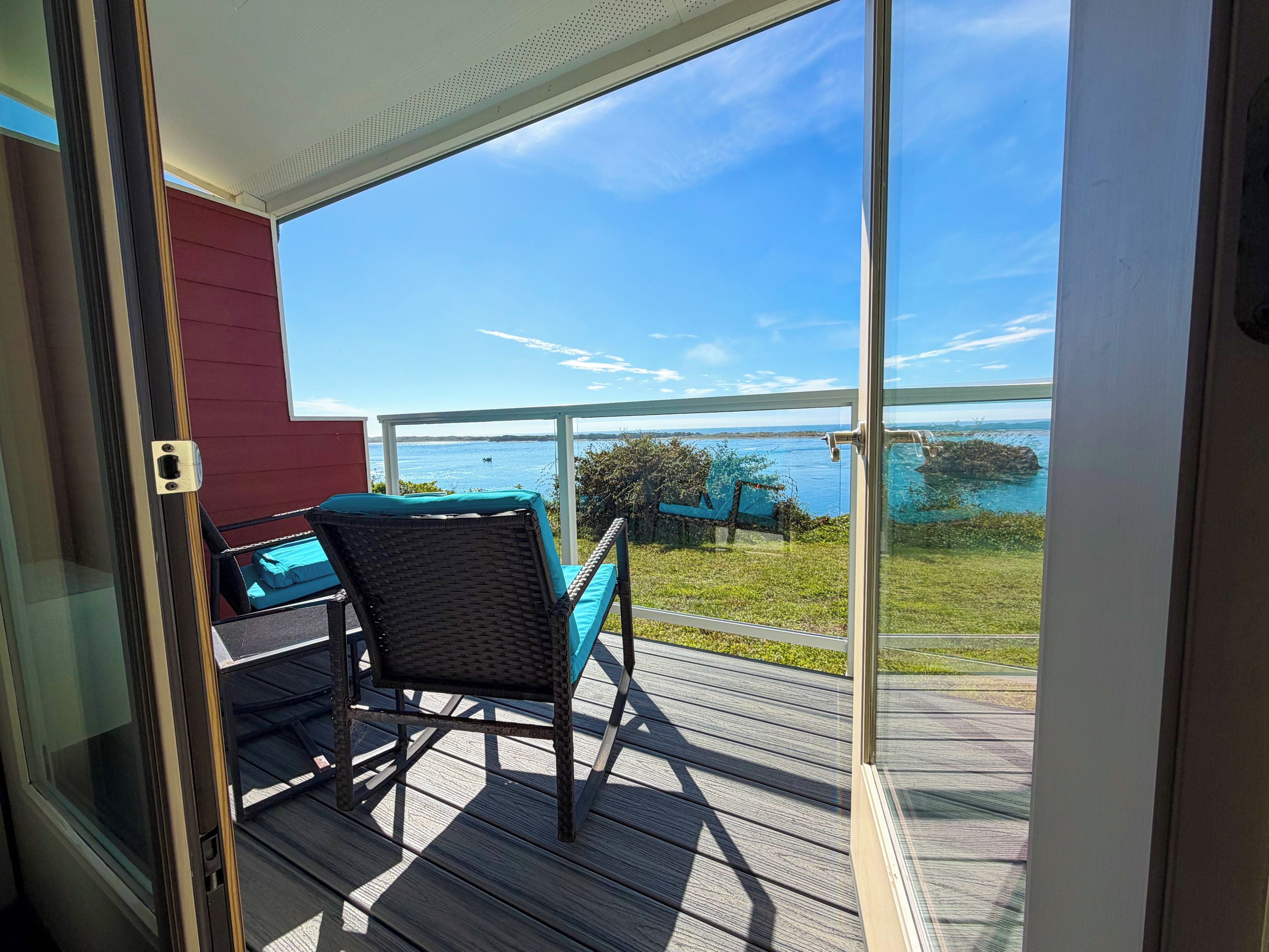 A balcony with a view of a body of water, a chair, and a table.