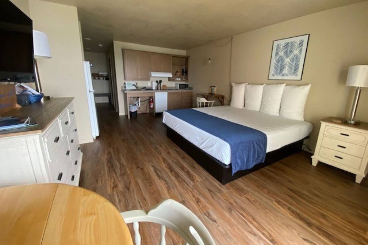 Ein kompaktes Hotelzimmer mit Bett, Schreibtisch, Stuhl, einer kleinen Küchenzeile und Esstisch.