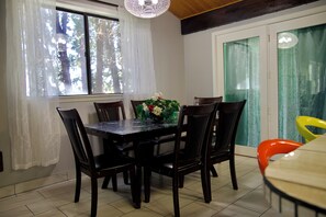 A dining area with a table and chairs, a vase with flowers, and a view through a window. - Bethesda Inn LLC , Modern, Comfort, Peaceful Stay (Boise)