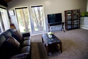 Ein Wohnzimmer mit einer Couch, einem Couchtisch mit einer Vase, einem Fernseher und einer Holzkassette.