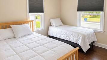 A bedroom with two beds, a ceiling fan, and windows with blinds.