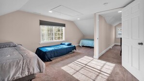 A bedroom with two beds, a window, and a door leading to another room.