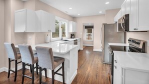 A modern kitchen with white cabinetry, a central island, and a dining area with bar stools.