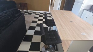 Una cocina con piso a cuadros, una mesa de madera y una silla negra.