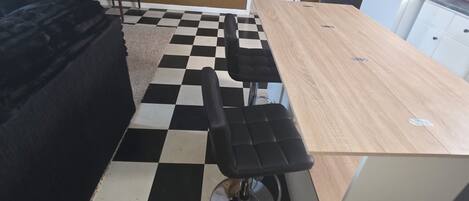 A kitchen with a checkered floor, a wooden table, and a black chair.