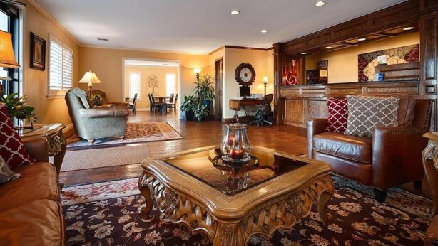 A spacious living room with a fireplace, leather sofas, and a coffee table. - Baymont by Wyndham McAlester Hwy 69 (McAlester)