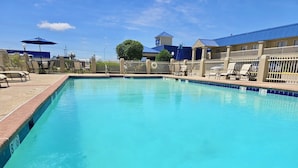 A rectangular swimming pool with a tiled edge, surrounded by lounge chairs and umbrellas. - Baymont by Wyndham McAlester Hwy 69 (McAlester)