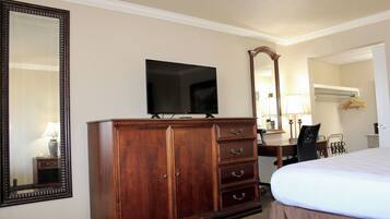 A hotel room with a large bed, a wooden dresser, a television, and a mirror.