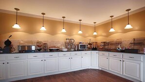 A kitchen with white cabinets, a wooden floor, and pendant lighting. - Baymont by Wyndham McAlester Hwy 69 (McAlester)