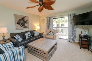 A living room with a sofa, armchair, coffee table, and a ceiling fan. - Ocean Village Club Condo R22 (St. Augustine)