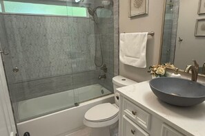 Een badkamer met een douche met glazen wand, een wit toilet en een grote wasbak.