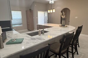 A kitchen with a marble countertop, a sink, and a dining area with chairs. - Country charm just minutes from Lake Conroe (Conroe)
