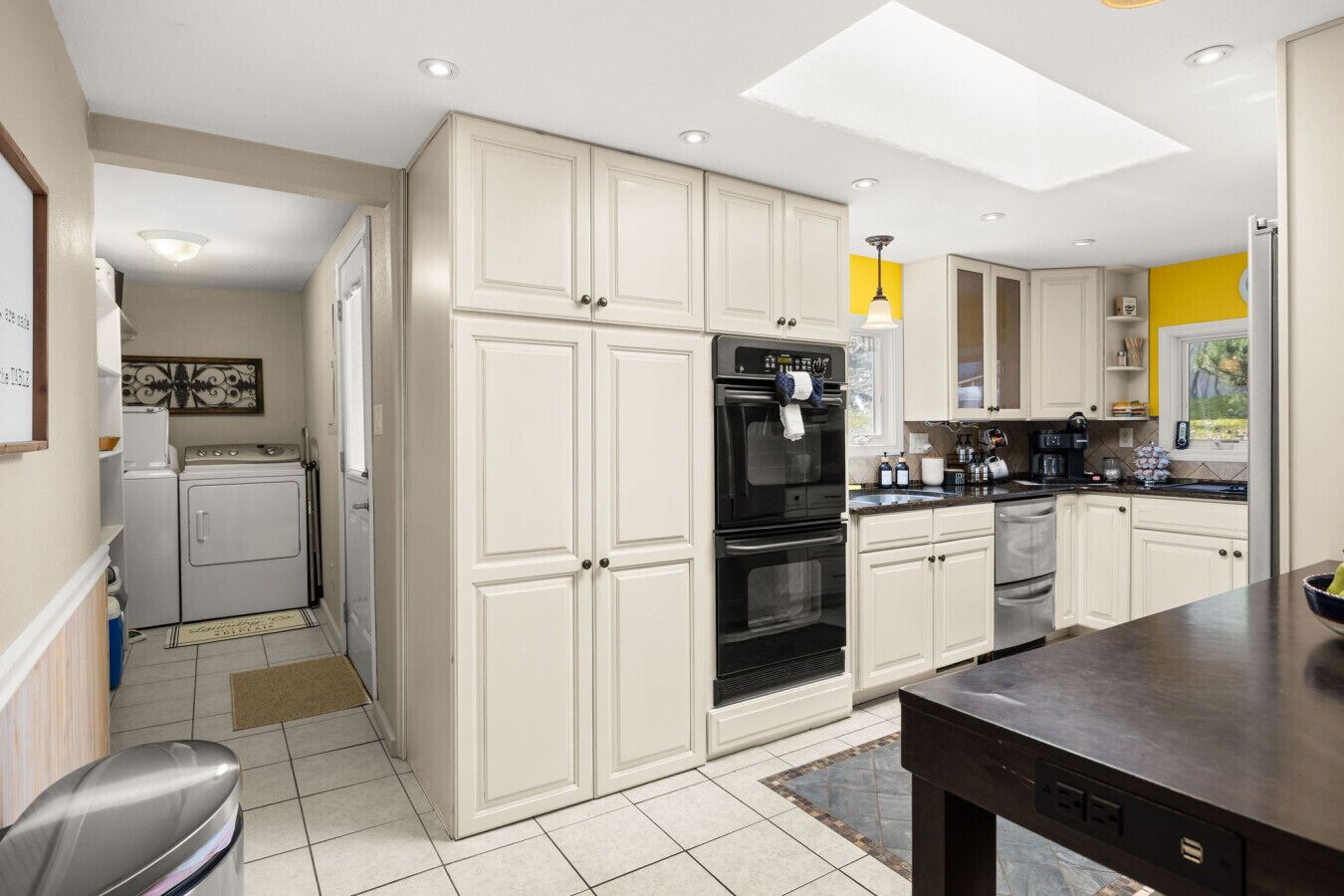 A kitchen with white cabinets, a black oven, and a coffee maker.