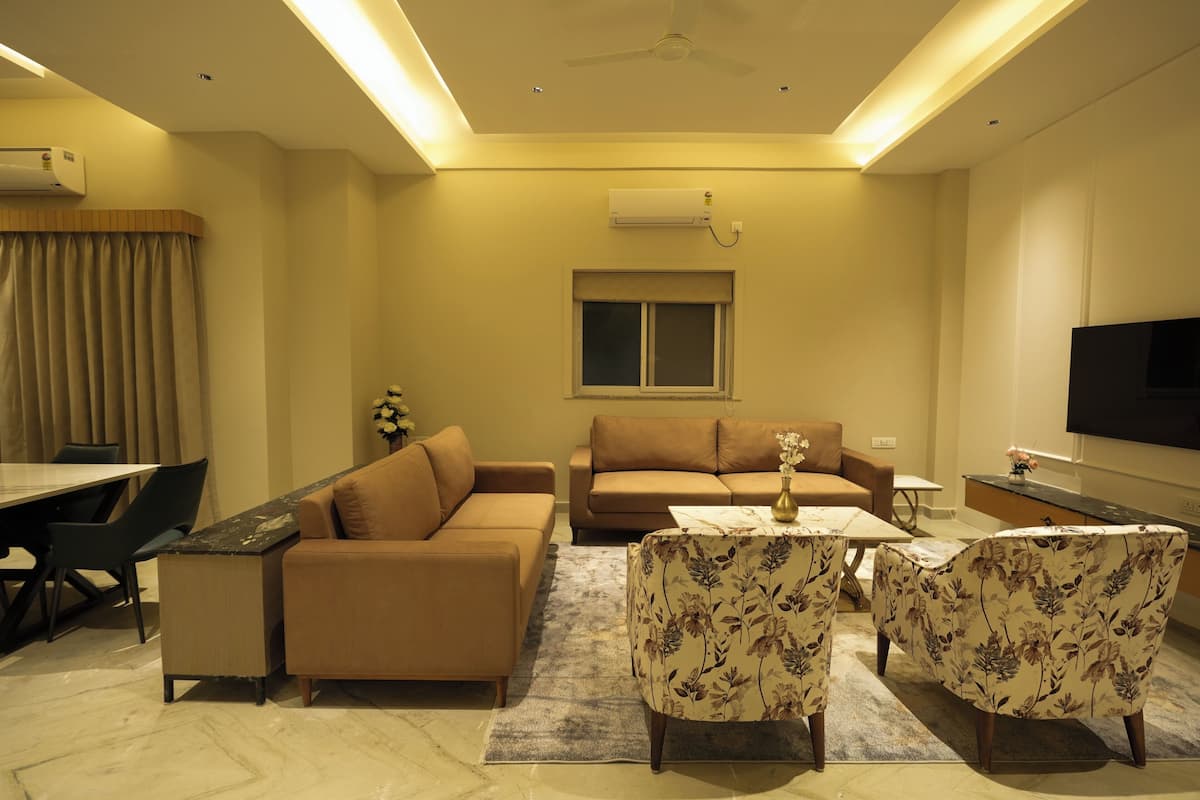 A living room with a sofa, a coffee table, and floral-patterned chairs.