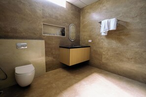 A bathroom with a toilet, sink, mirror, and towel rack. - The One Jubilee (Hyderabad)