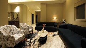 A modern living room with two sofas, a coffee table, and floral armchairs. - The One Jubilee (Hyderabad)
