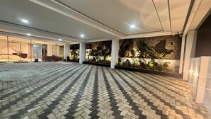 A spacious indoor area with a patterned floor, columns, and a wall with plants. - The One Jubilee (Hyderabad)