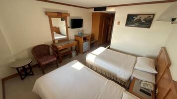 Quarto de hotel com duas camas, uma escrivaninha com cadeira, televisão e um quadro na parede.
