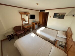 A hotel room with two beds, a desk with a chair, a television, and a painting on the wall. - Hadthong Hotel (Prachuap Khiri Khan)