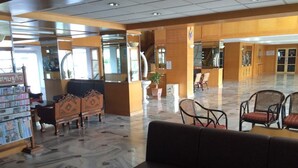 A lobby with a reception desk, seating area, and a staircase. - Hadthong Hotel (Prachuap Khiri Khan)