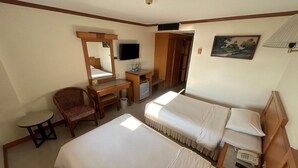 A hotel room with two beds, a desk with a chair, a television, and a painting on the wall. - Hadthong Hotel (Prachuap Khiri Khan)