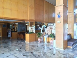 A lobby with marble flooring, wooden reception desk, and decorative statues. - Hadthong Hotel (Prachuap Khiri Khan)