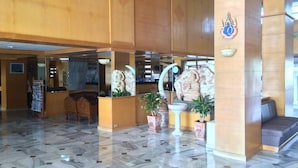 A lobby with marble flooring, wooden reception desk, and decorative statues. - Hadthong Hotel (Prachuap Khiri Khan)