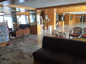 A lobby with a reception desk, seating area, and a staircase. - Hadthong Hotel (Prachuap Khiri Khan)