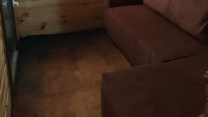 A wooden cabin interior with a brown sofa and a small window.