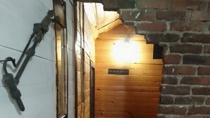 A narrow hallway with wooden walls and a brick archway leading to a room labeled "The Chamber of Secrets."