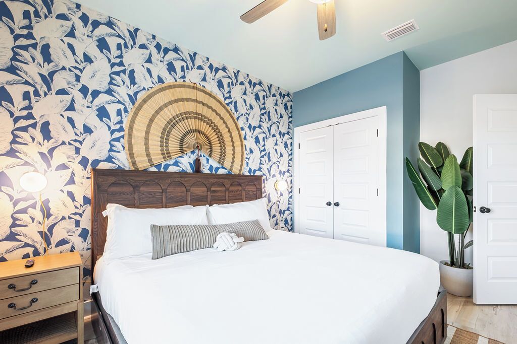 A bedroom with a bed, nightstand, and a large fan.