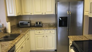 A kitchen with white cabinets, a stainless steel refrigerator, a toaster, and a microwave. - Beachfront location, magnificent views for an unforgettable serene escape (Naples)