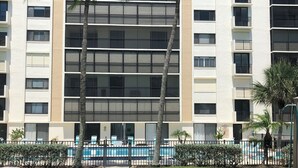 A multi-story hotel with a swimming pool, palm trees, and a pathway leading to the pool. - Beachfront location, magnificent views for an unforgettable serene escape (Naples)