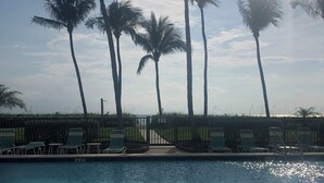 A pool with clear blue water, surrounded by palm trees and lounge chairs. - Beachfront location, magnificent views for an unforgettable serene escape (Naples)