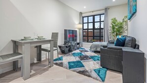 Ein modernes Wohnzimmer mit Essbereich, einer Couch und einem großen Fenster mit Vorhängen.