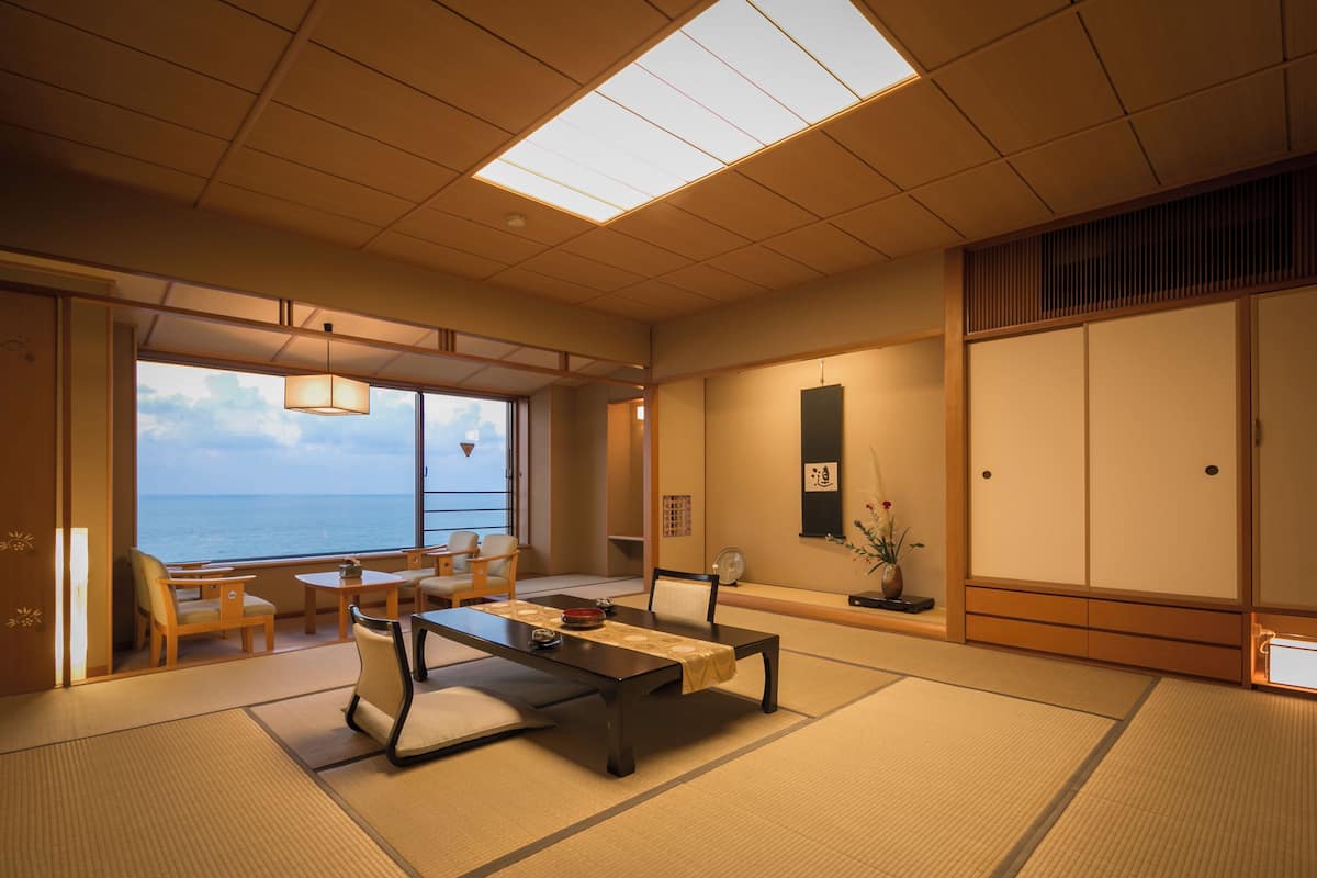Une pièce de style japonais traditionnel, avec un sol recouvert de tatamis, une table basse agrémentée d’un chemin de table et des portes coulissantes.