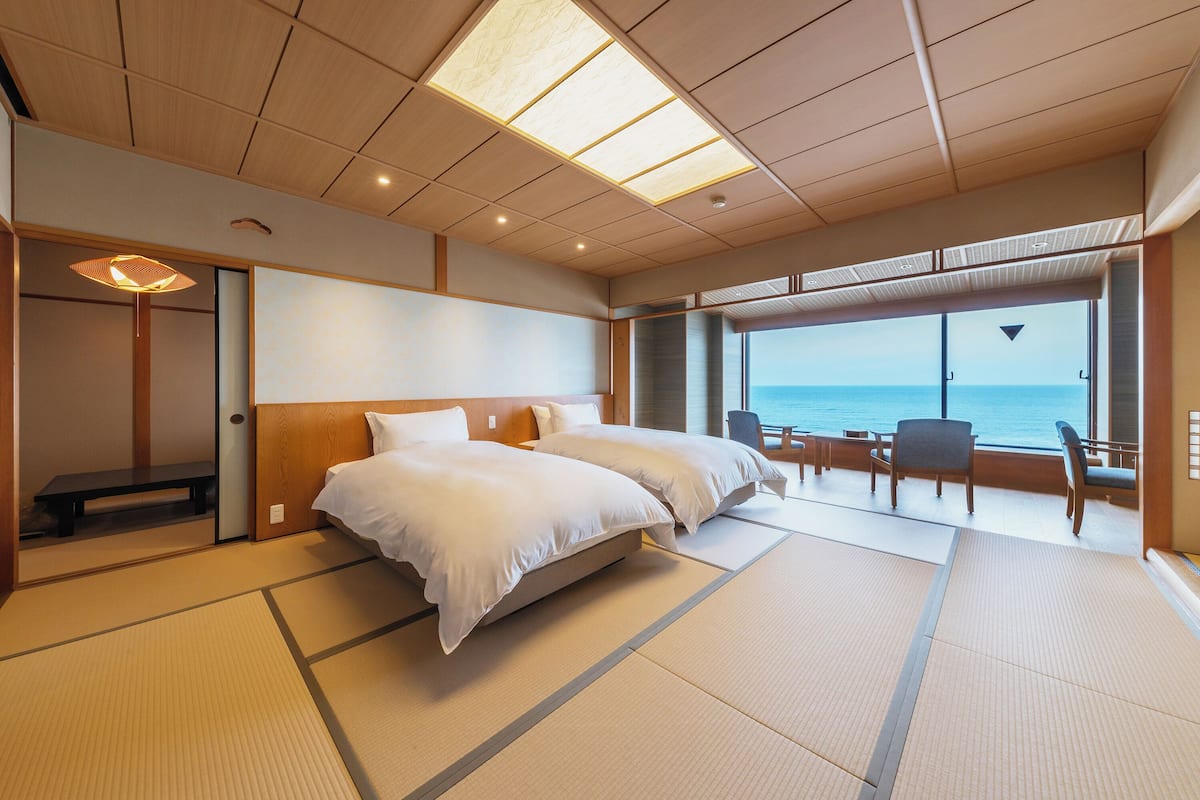 Une chambre avec un lit, un banc et une vue sur la mer.