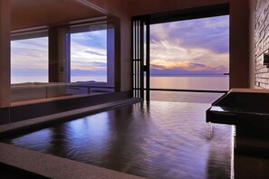 Una piscina interior moderna con vista al atardecer sobre el agua.