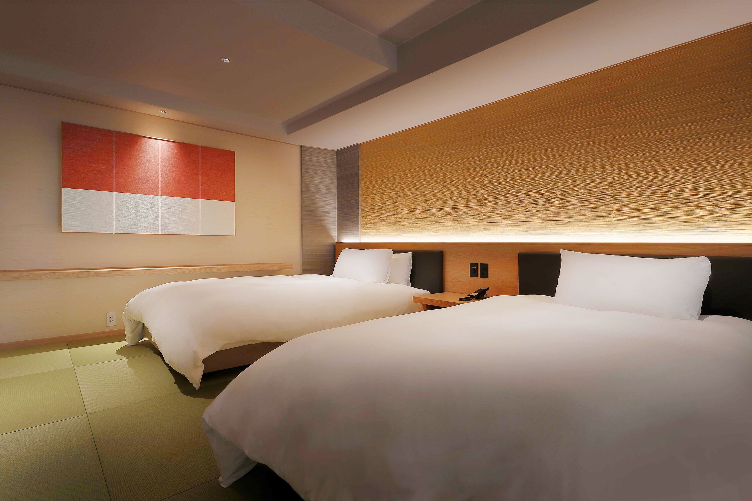 A hotel room with two beds, a wooden headboard, and a wall-mounted artwork.