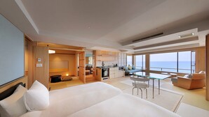 A modern hotel room with a large bed, a dining area, and a view of the sea. - yuusuiteiisagoya (Tsuruoka)