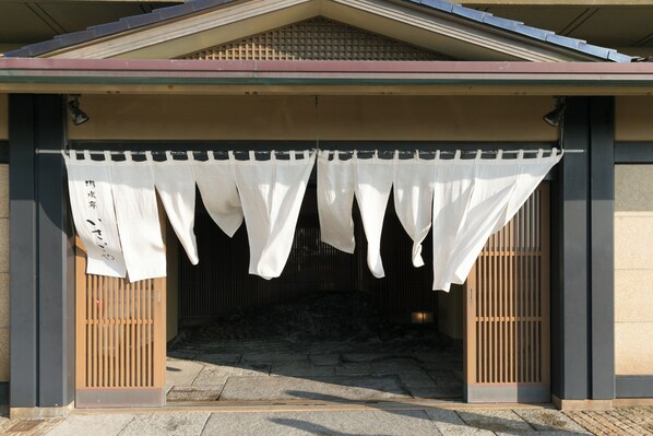 A traditional Japanese building entrance with a covered porch, wooden slats, and a stone pathway. - yuusuiteiisagoya (Tsuruoka)