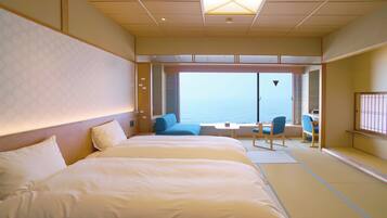 Habitación de hotel con una cama grande, zona de estar con vista al mar y puerta corredera que da al balcón.