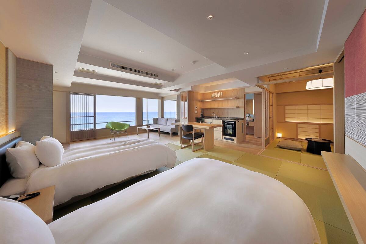 Une chambre d’hôtel avec deux lits, une kitchenette et vue sur la mer.
