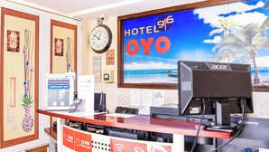 A hotel reception desk with a clock, a suggestion box, a complaint box, and a sign indicating check-in and check-out times. - Hotel 916 (Batu Caves)