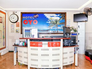 A hotel reception desk with a clock, a suggestion box, a complaint box, and a sign indicating check-in and check-out times. - Hotel 916 (Batu Caves)