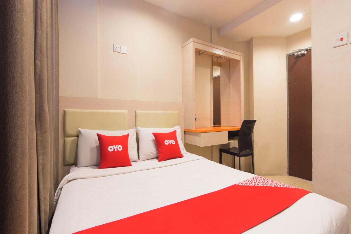 A hotel room with a bed, a desk, and a chair.