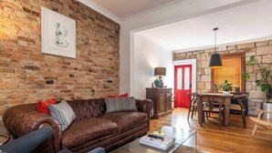 Un salon chaleureux avec un canapé en cuir marron, une table basse et un mur en briques.